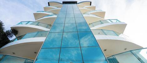 A modern building with a glass facade and multiple balconies.
