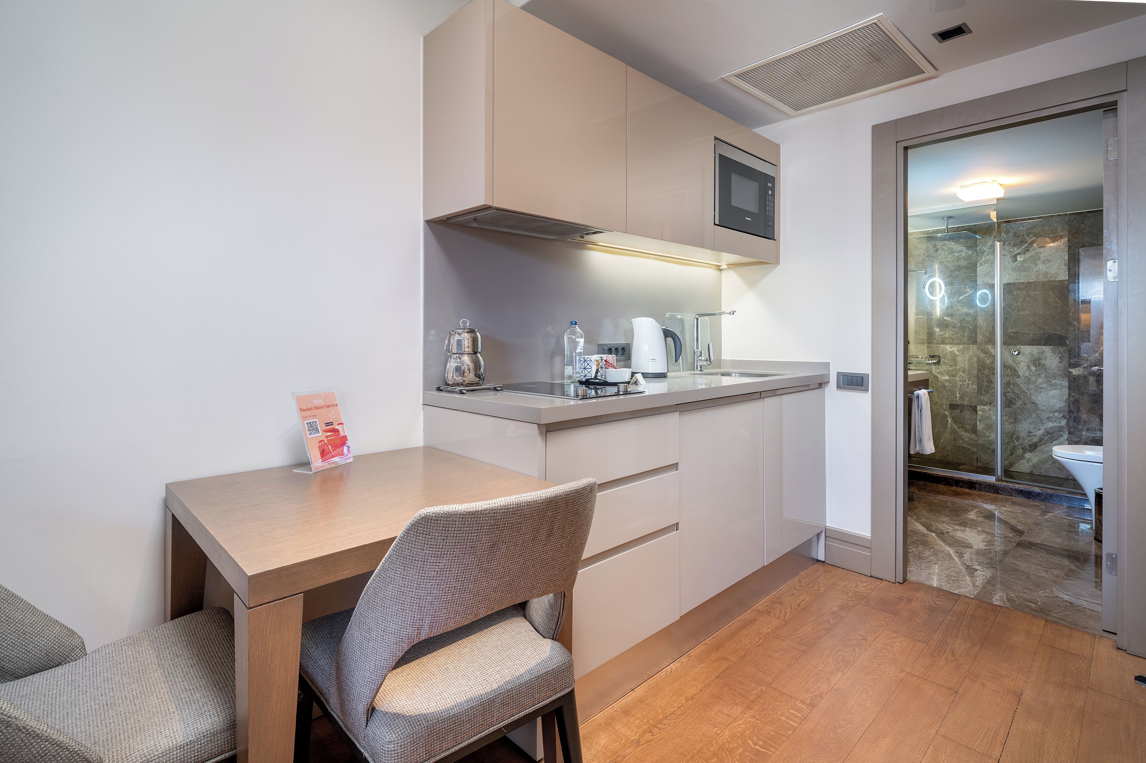 A modern kitchen with a dining area, including a table, chairs, and a coffee machine.