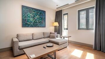 A modern living room with a sectional sofa, a small side table, a lamp, and a large abstract painting on the wall.