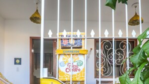 A yellow wall with a white gate, a woven mat, and a table with chairs. - Apartamentos Pipa Centro (Tibau do Sul)