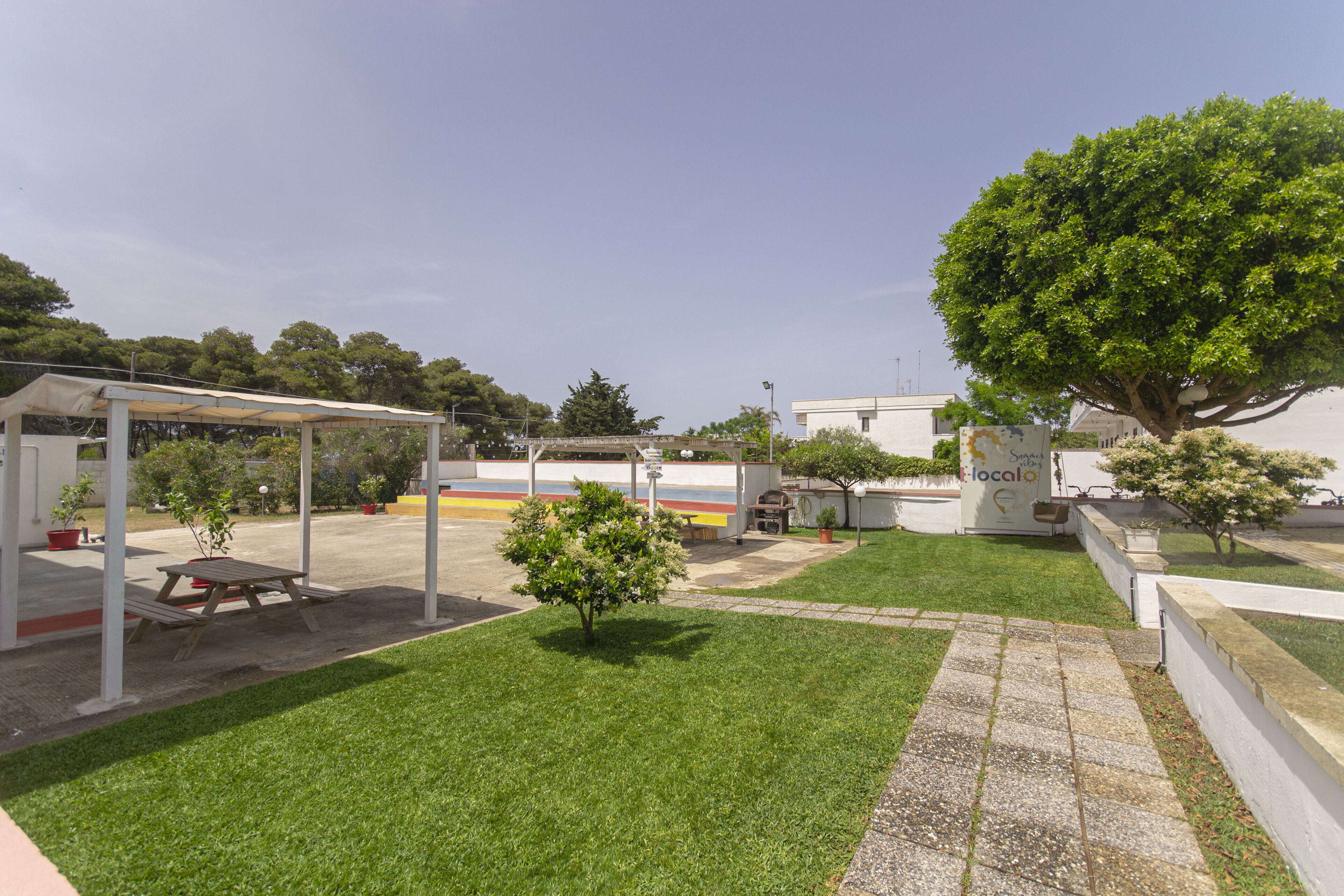 A courtyard with a picnic table, a covered seating area, and a large tree.