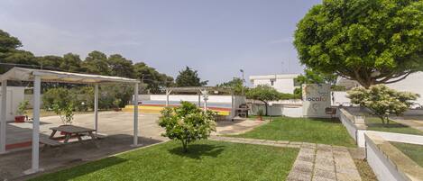 A courtyard with a picnic table, a covered seating area, and a large tree.