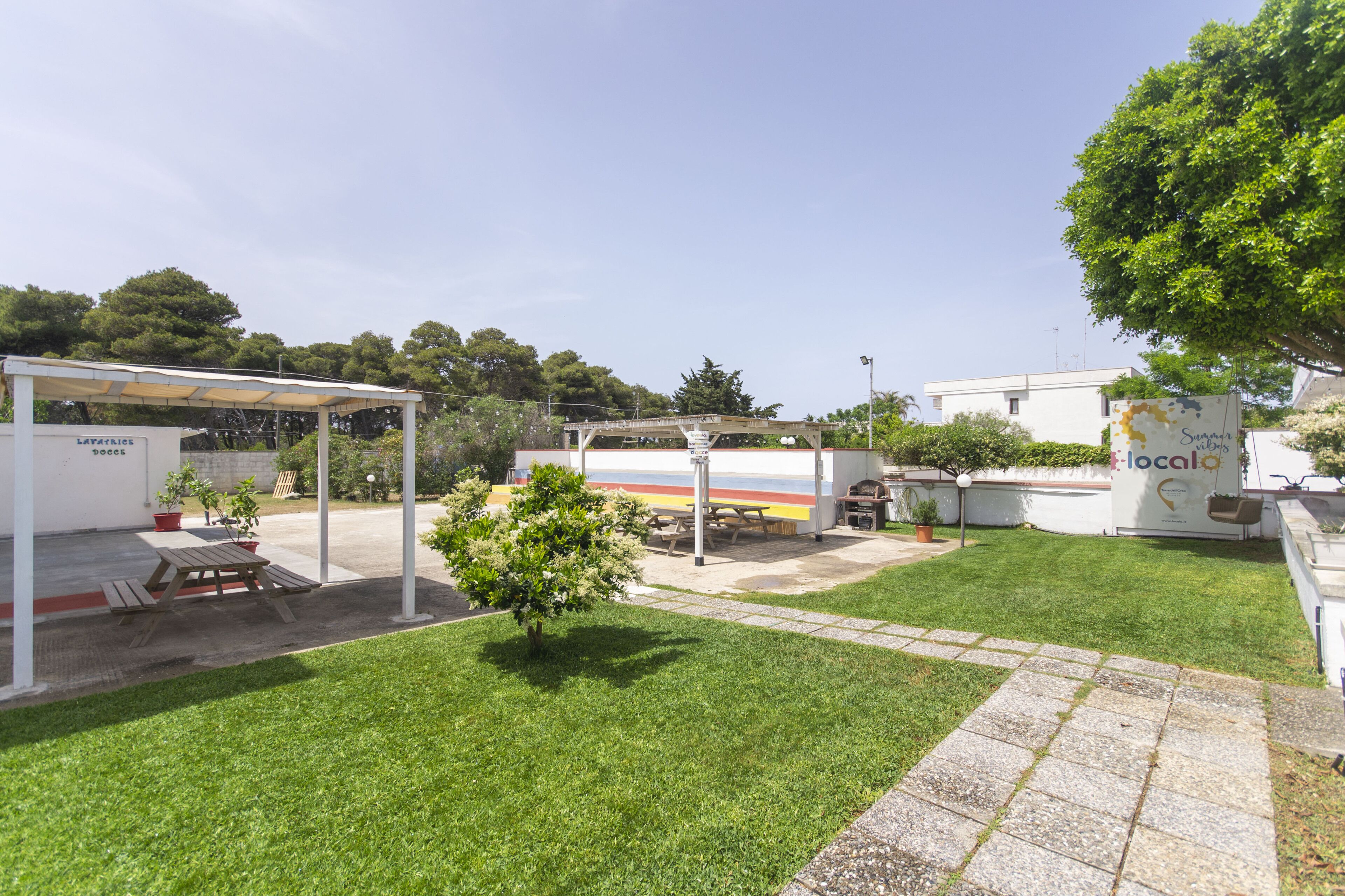 A courtyard with a picnic table, a covered seating area, and a building with a sign.