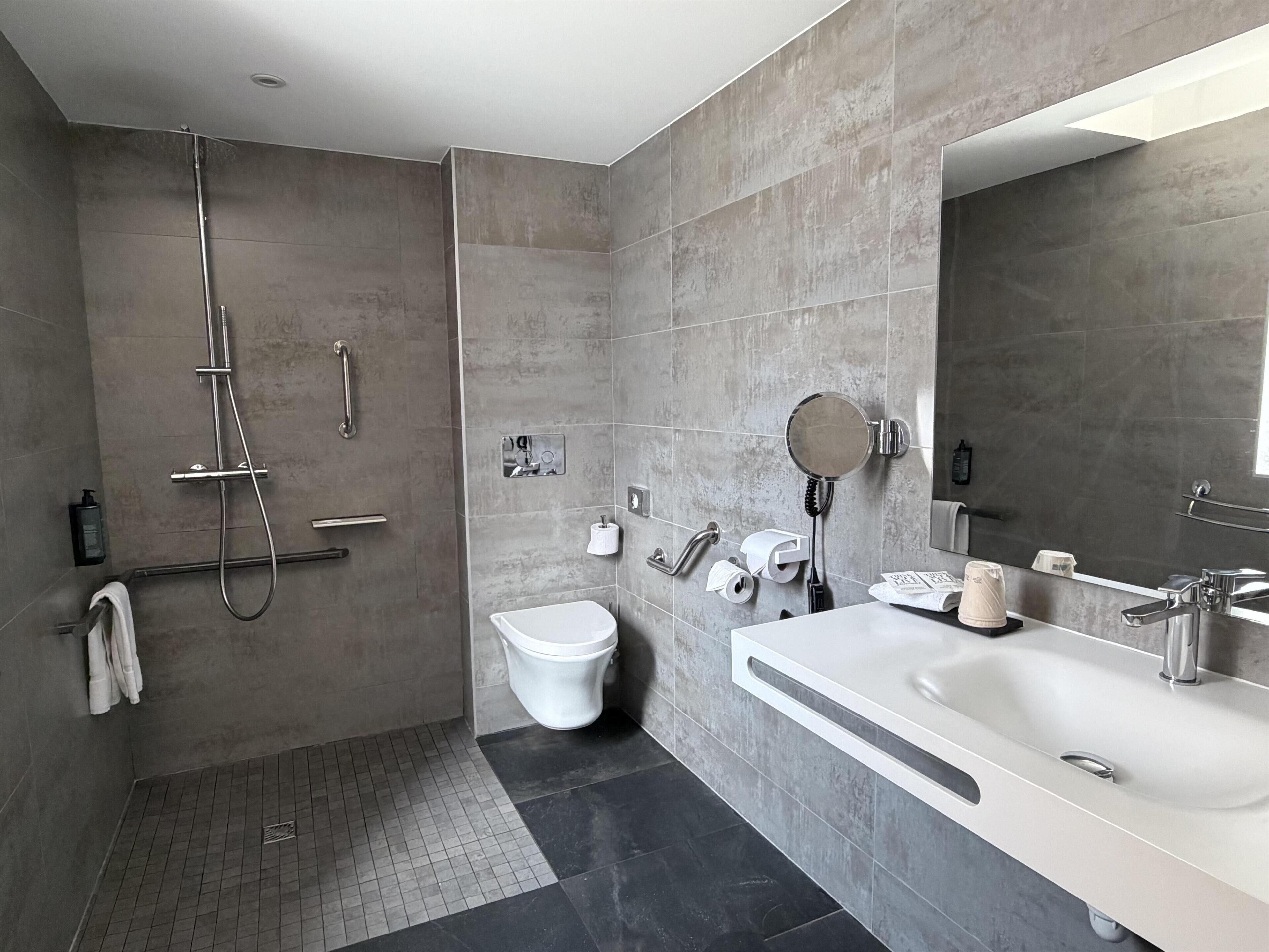 Ein modernes Badezimmer mit begehbarer Dusche, Toilette und Waschbecken.