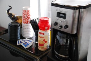 A coffee maker on a tray with condiments and utensils. - Westworld Country Inn (Hubbard)