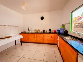 Uma cozinha com bancada de madeira, pia e relógio na parede.