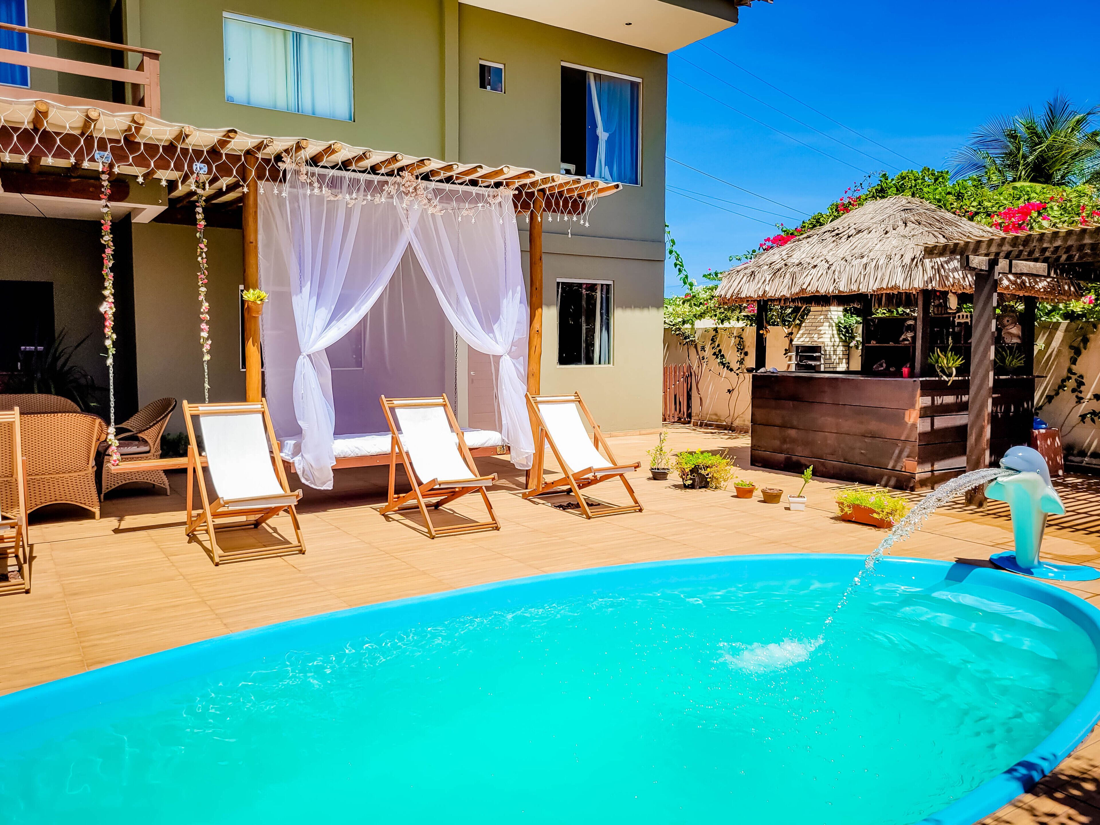 Uma área de piscina com espreguiçadeiras e um toldo.