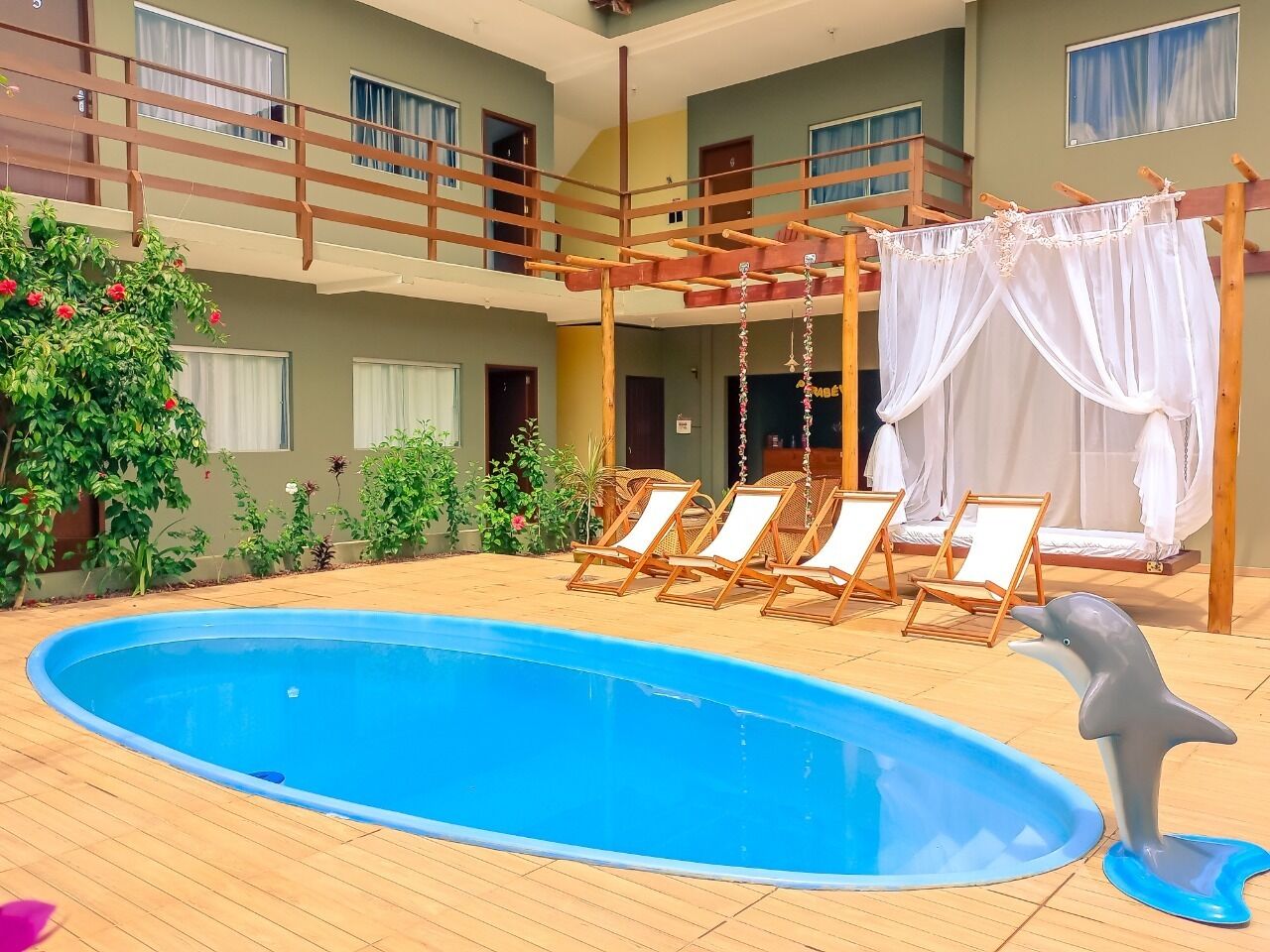 A pool area with a dolphin statue, lounge chairs, and a wooden deck.