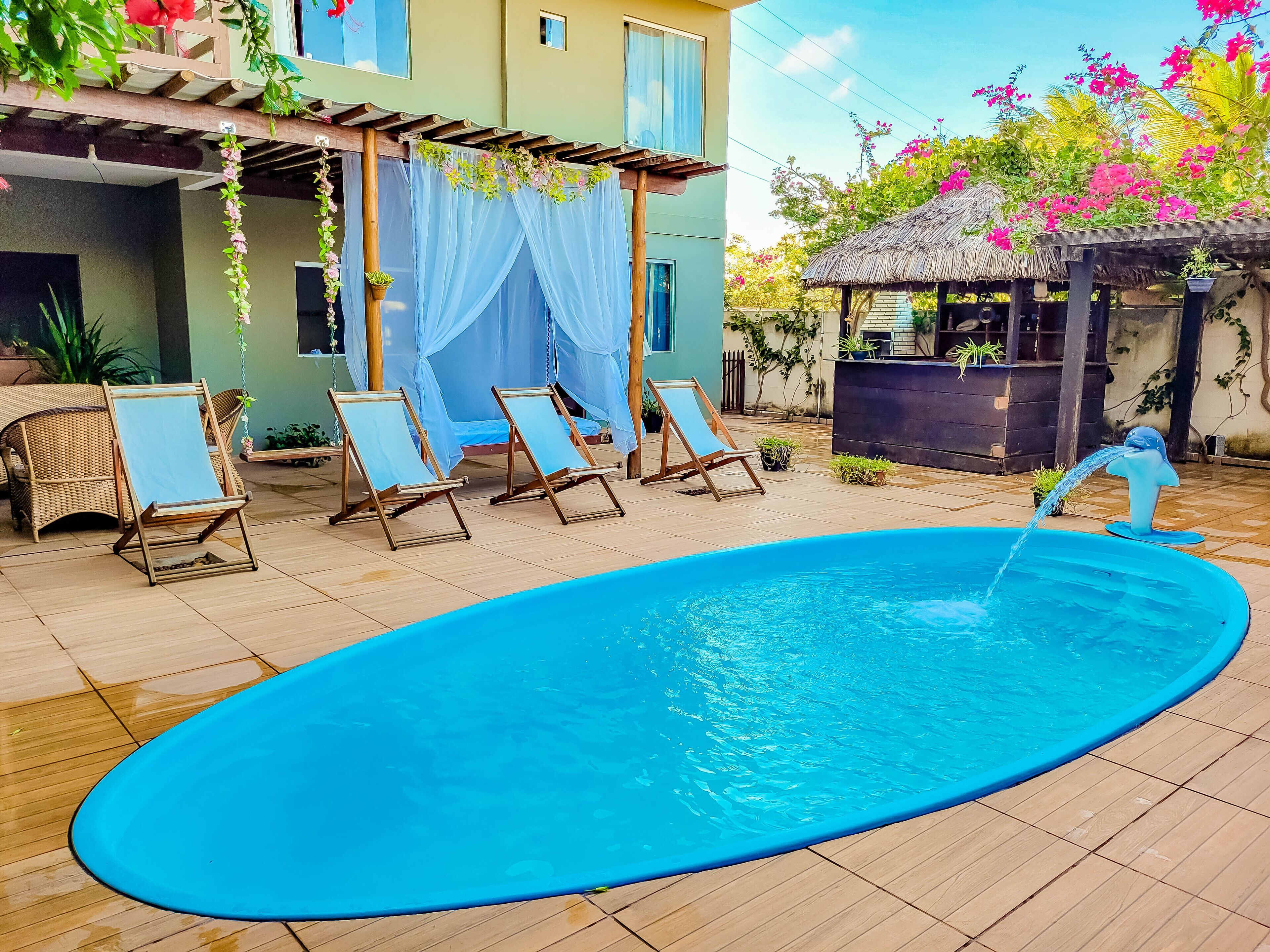 En utomhuspool med solstolar och en pergola som är dekorerad med tyg.