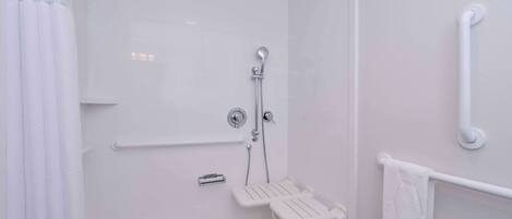 A modern bathroom with a walk-in shower, grab bars, and a white towel rack.