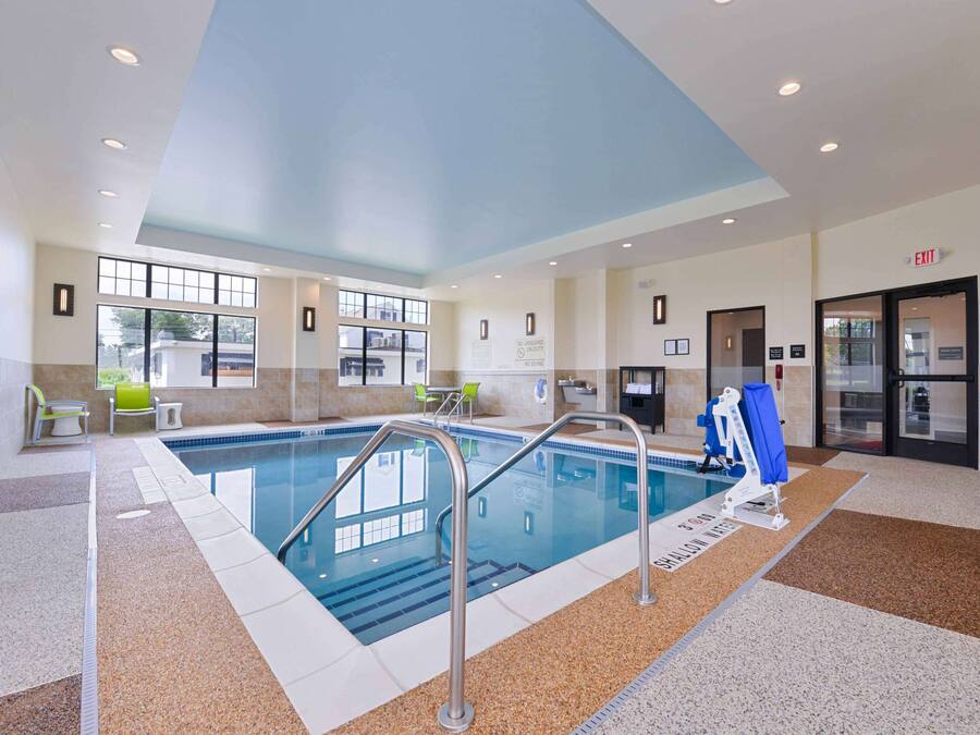 An indoor swimming pool with clear glass walls, a blue ceiling, and a lifeguard chair.