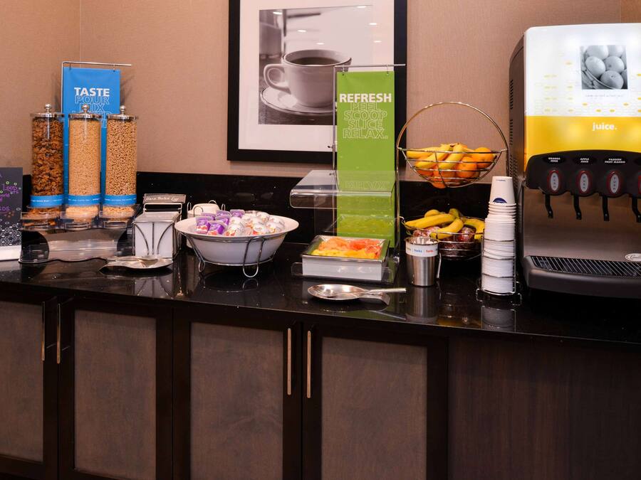 Un área de bufé con diversas opciones de comida, una máquina de café y un dispensador de zumo.