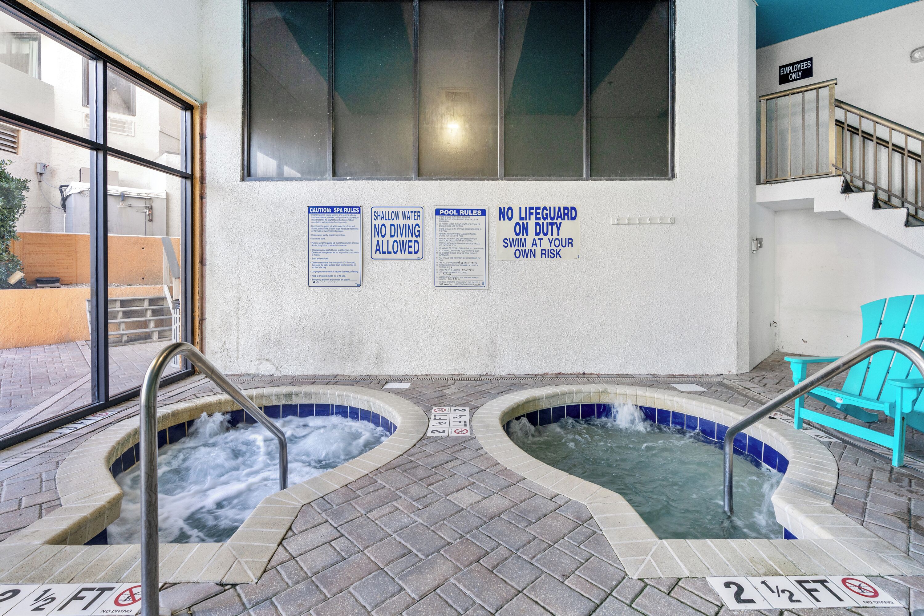 Een wellnessruimte met twee bubbelbaden, een trap en veiligheidssignalen.