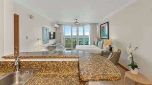 A hotel room with a kitchen area, a bed, a balcony with a view, and a ceiling fan. - Scenic Studio ° Lagoon Views & Private Balcony (San Juan)
