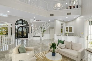 A spacious living area with a high ceiling, a staircase, and a large window. - 5-acre Luxe 5B Getaway @Murrieta | Pool, Hot Tub (Murrieta)
