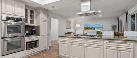 A modern kitchen with white cabinetry, stainless steel appliances, and a skylight.