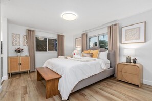 A modern bedroom with a large bed, bedside tables, a bench, and a window with curtains. - Luxe 5B Oasis | Pool, Spa & Views! @Chino Hills (Chino Hills)
