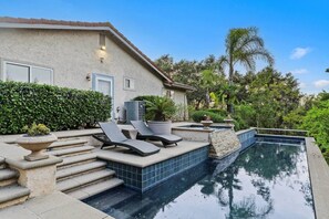 A swimming pool with lounge chairs, a stone staircase, and a house with a tiled roof. - Luxe 5B Oasis | Pool, Spa & Views! @Chino Hills (Chino Hills)