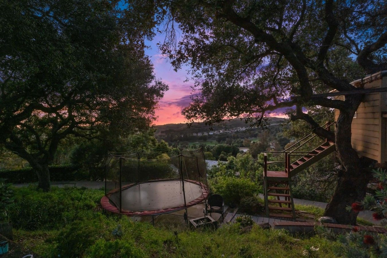 A circular outdoor area with a wooden bench and a staircase leading to a building.