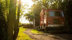 A red truck parked on a gravel path surrounded by trees. - Cabin Sleeps 2 With Pets Welcome (Skegness)
