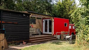 A small cabin with a porch, a red fire truck, and a grill in the yard. - Cabin Sleeps 2 With Pets Welcome (Skegness)