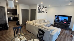 Una sala moderna con sofá, televisor y zona de comedor.