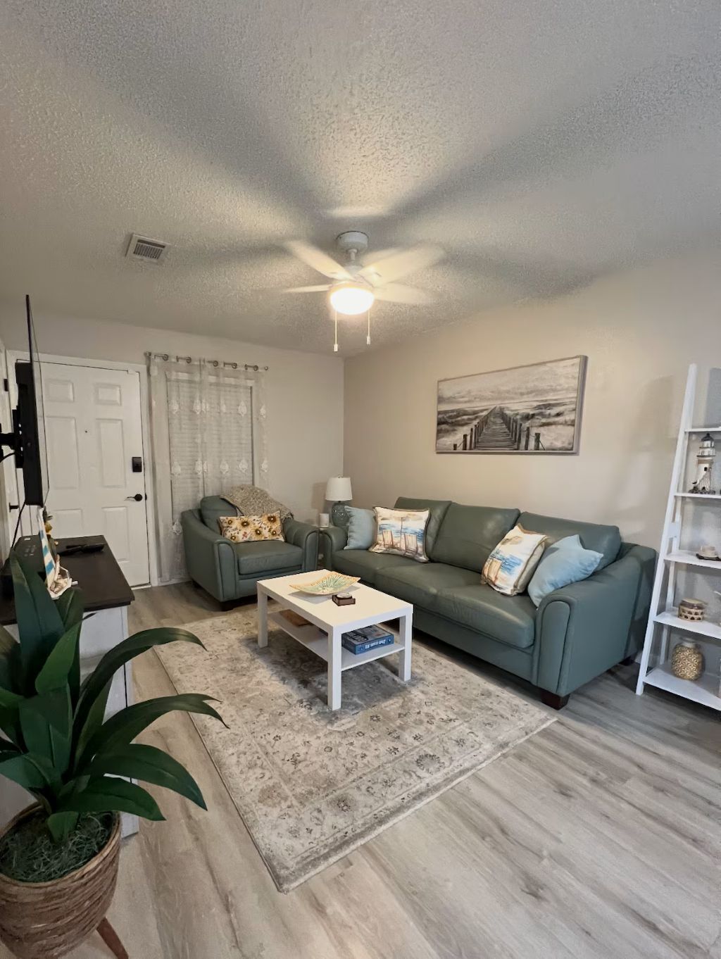 A living room with a sofa, coffee table, and a ceiling fan.