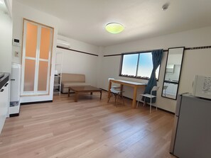 A compact living space with a kitchenette, a sofa, a dining table, and a window with curtains. - 9 minutes from JR Namba Station/Airport Bus Terminal, 6 minutes from JR Ashiwarabashi Station, close to both Shinsaibashi and Kyocera Dome Osaka, Ohara 402 (大阪市浪速区塩草３丁目)