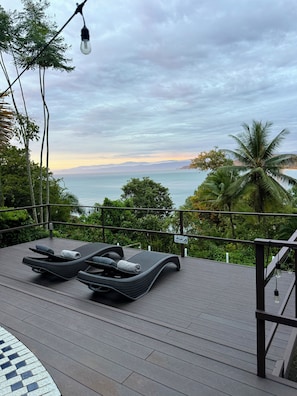 A deck with lounge chairs and a view of the sea.