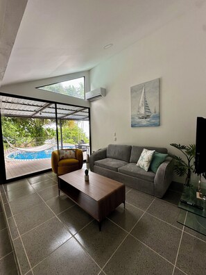 A modern living room with a sofa, armchair, coffee table, and a painting of a sailboat. - Full accommodation with swimming pool and ocean view (Agujitas (Drake))