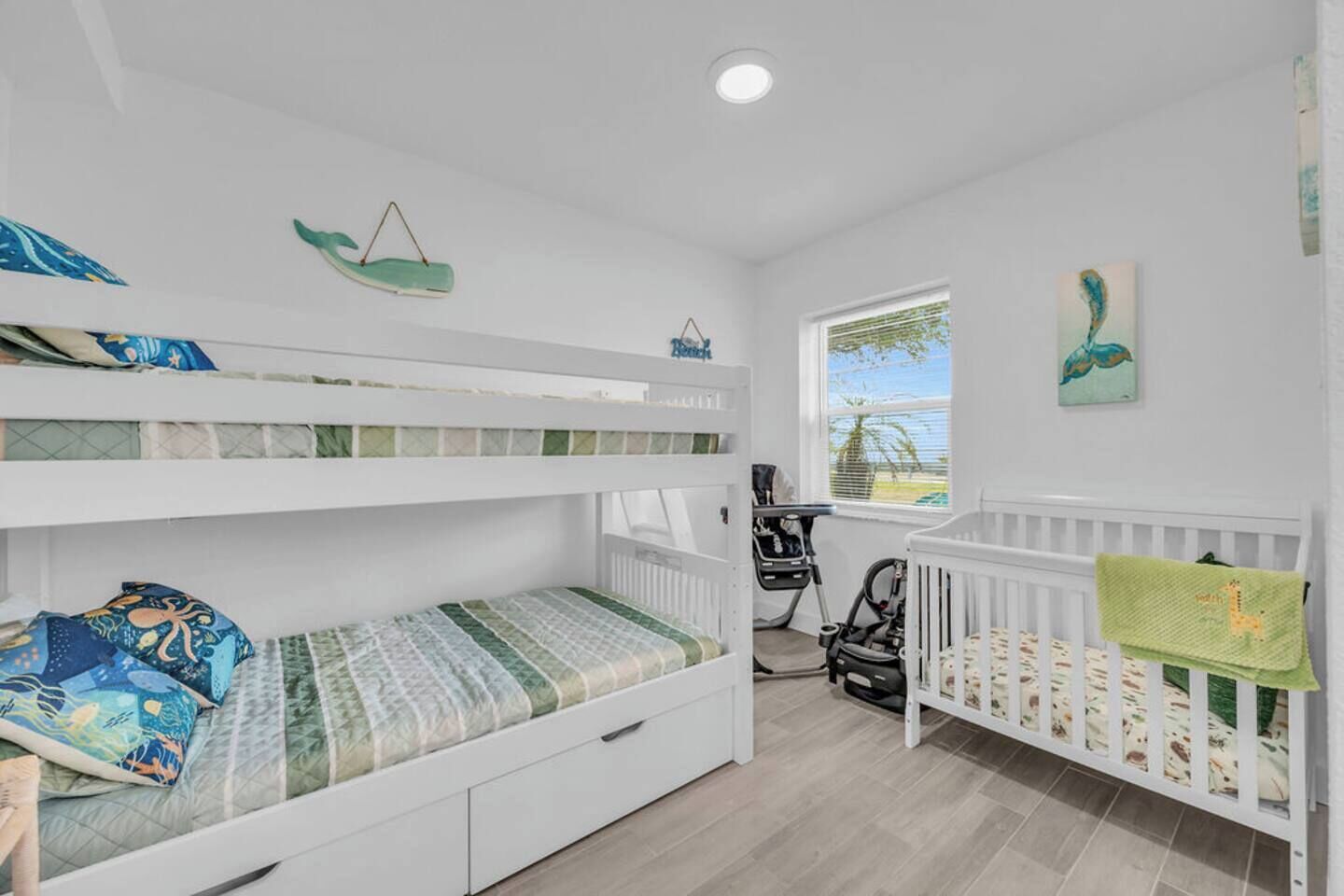 A child's bedroom with bunk beds, a desk, and a crib.