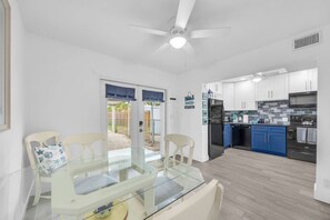 A modern kitchen with white cabinets, a black refrigerator, and blue accents. - Cozy Melbourne Retreat | Indian river | Beaches (Melbourne)