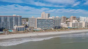 A coastal hotel with multiple high-rise buildings, a beach, and a swimming pool. - Mariner’s Escape - Ocean View 3BR Sleeps 12 (Myrtle Beach)