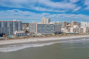 A coastal hotel with multiple high-rise buildings, a beach, and a swimming pool. - Mariner’s Escape - Ocean View 3BR Sleeps 12 (Myrtle Beach)