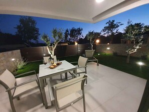An outdoor patio with a table and chairs, a wine glass, and a bottle. - Holiday apartment with pool and air conditioning (Sv. Filip i Jakov)