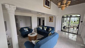A spacious living area with two blue sofas, a round coffee table, and a large window with a view.