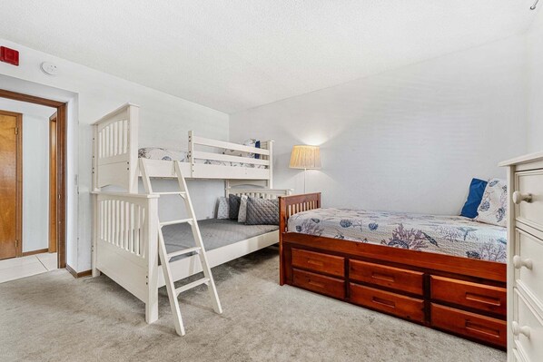 A bedroom with a bunk bed, a desk, a lamp, and a dresser. - Cocoa Beach Corner Unit Condo. Private Balcony. Heated Pool & Hot Tub ☀️ (Cocoa Beach)