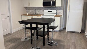 Een moderne keuken met witte kasten, een roestvrijstalen magnetron, een dubbele oven en een witte koelkast.