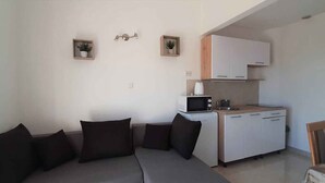 Un espai habitable pràctic amb un sofà, una cuineta i una petita zona de menjador.