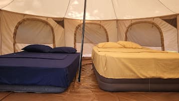 A tent with two beds, one with a blue mattress and the other with a yellow mattress.