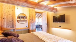 A bedroom with a bed, a TV, a wooden ceiling, and a circular mirror. - La Caretta - BONNEVAL SUR ARC (BONNEVAL SUR ARC)