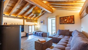 A modern living room with a wooden ceiling, a sectional sofa, a fireplace, and a dining area. - La Caretta - BONNEVAL SUR ARC (BONNEVAL SUR ARC)