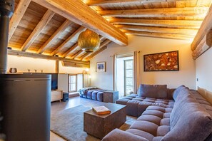 Ein modernes Wohnzimmer mit Holzboden, einem Ecksofa, einem Kamin und einem Essbereich.