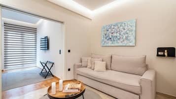 A living room with a sofa, a coffee table, a painting, and a television.