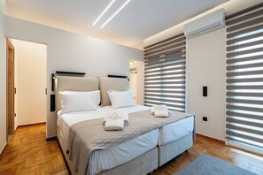 Une chambre à coucher moderne, avec un lit, des tables de chevet et une fenêtre équipée de stores.