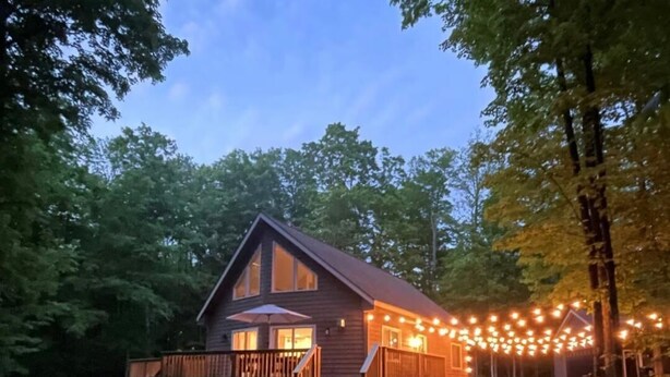 Eine Hütte mit einer Veranda, Sitzgelegenheiten im Freien und Lichterketten.