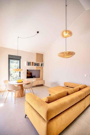 Ein modernes Wohnzimmer mit einer Couch, einem Esstisch und einem Fernseher.