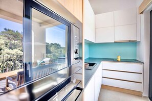 Eine moderne Küche mit großem Fenster, Blick ins Freie und minimalistischem Design.