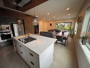 A modern kitchen with a central island, built-in appliances, and a dining area with a view.
