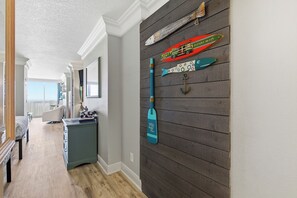 A hallway with a wooden wall, a blue paddleboard, and a red and green boat. - Oceanfront Balcony Views • Bright Studio • Clean & Great Value (Daytona Beach)